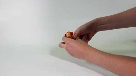 hands manipulate a toy monkey on table