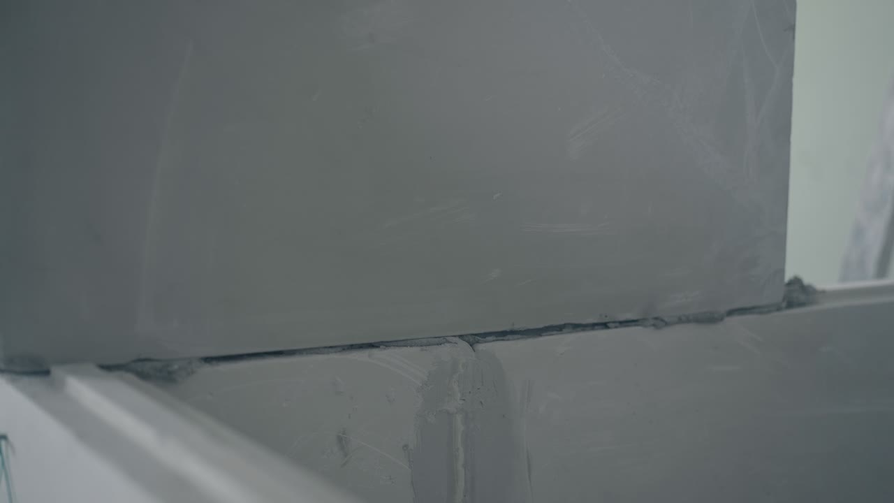 hombre sostiene placa de yeso y pone en la construcción de la pared