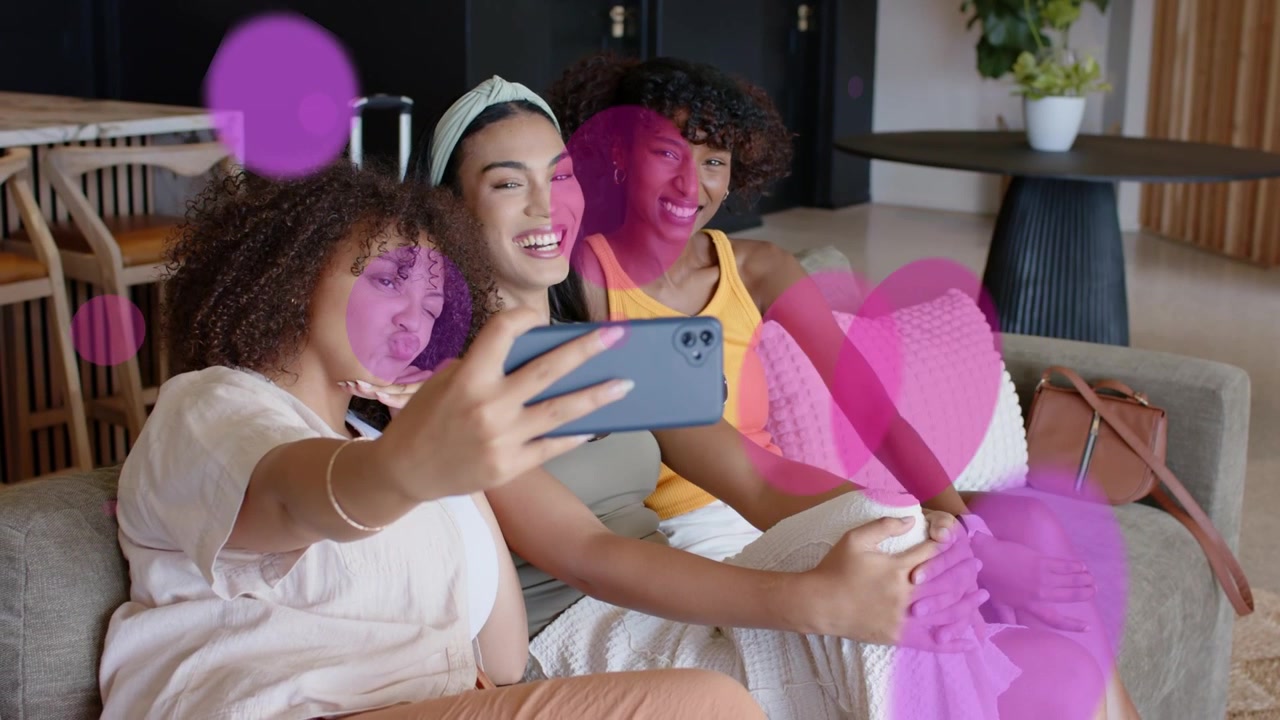 Donna a sinistra che estende il telefono avviando sovrapposizioni rosa mentre tre donne posano, rivedendo lo scatto per annunci pubblicitari.