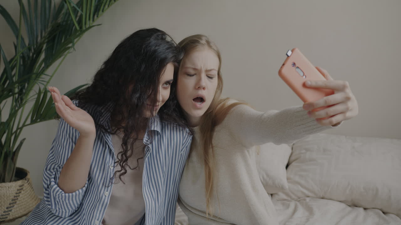 Two young women taking a selfie on a bed