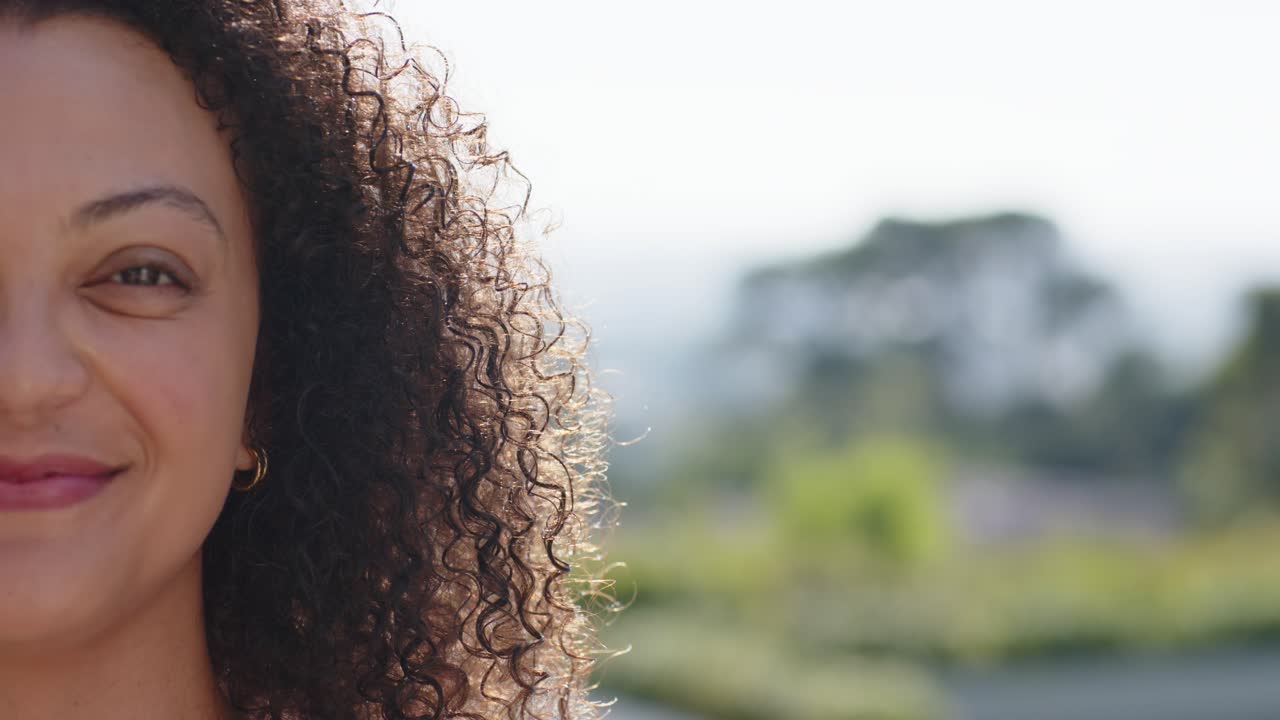 Donna africana che reagisce a un segnale fuori campo, ammiccando, sorridendo e ridendo, in cima a una collina, con orecchino a cerchio, spazio per il testo