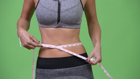 young woman measuring her fit and healthy body
