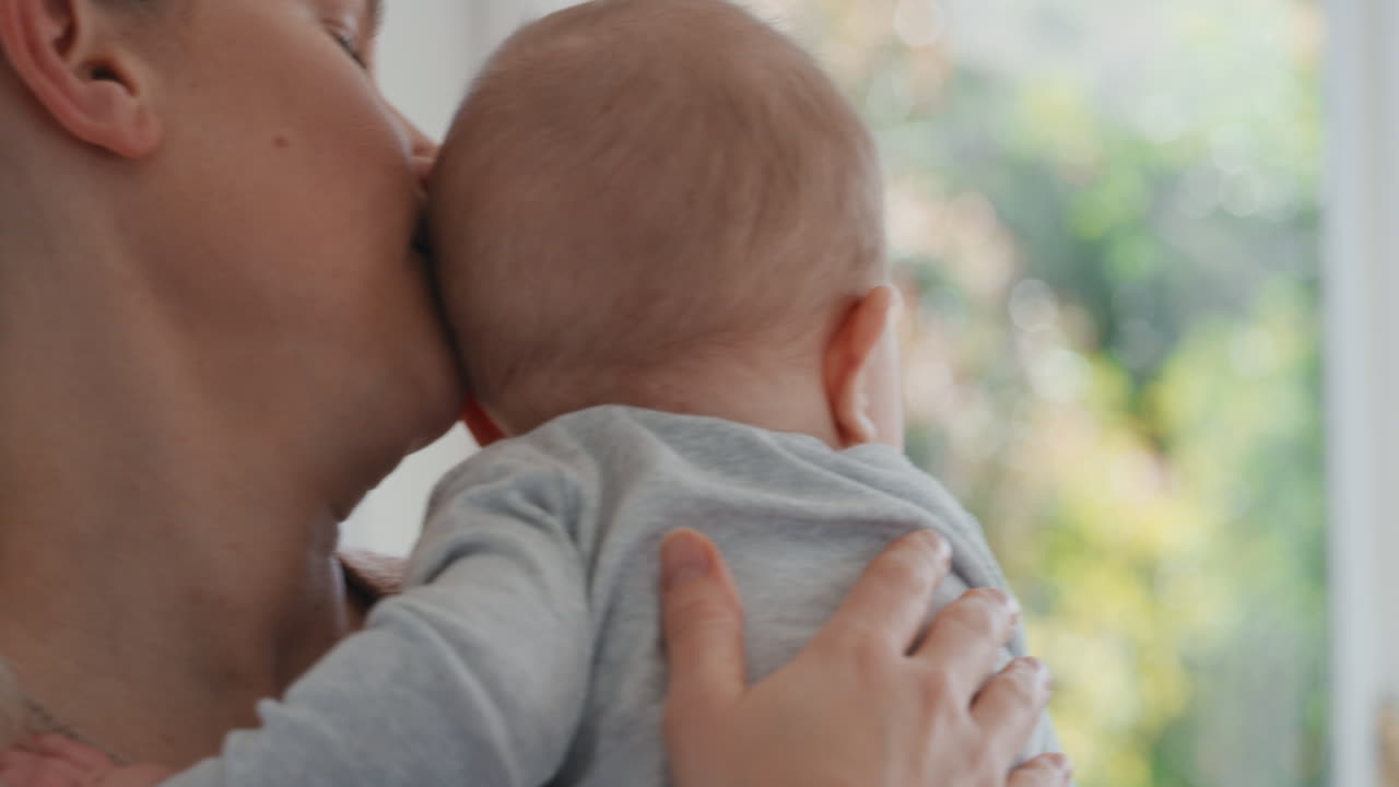 사랑하는 어머니가 아기를 안고 신생아를 진정시키고 엄마는 부드럽게 아기를 진정시켜 집에서 양육하는 모성 생활을 즐긴다 4k