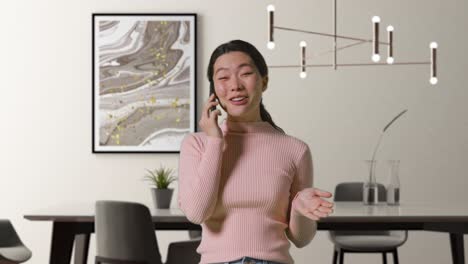 woman indoors at home in dining room talking on mobile phone