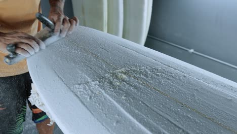 unrecognizable man polishing surfboard with special tool