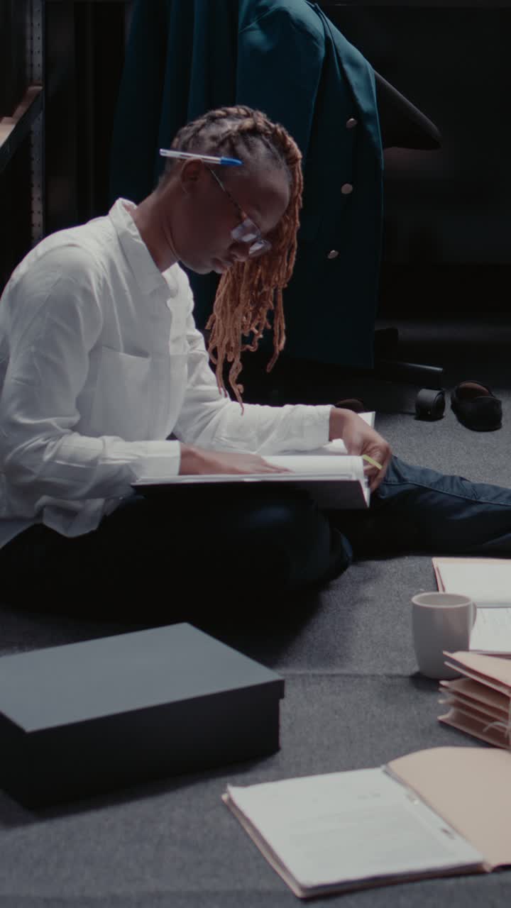 Vertical video: African american detective looking at case files on floor