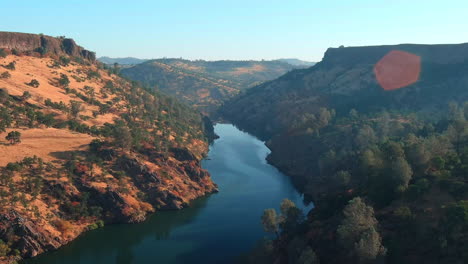 aerial flyover of a beautiful canyon river at sunset near lake tulloch in california