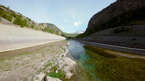 FPV-Drohne-Fliegt-über-Asphaltierte-Straße-Und-Entlang-Des-Flusses-Mont-Cenis,-Luftaufnahme-Nach-Vorn