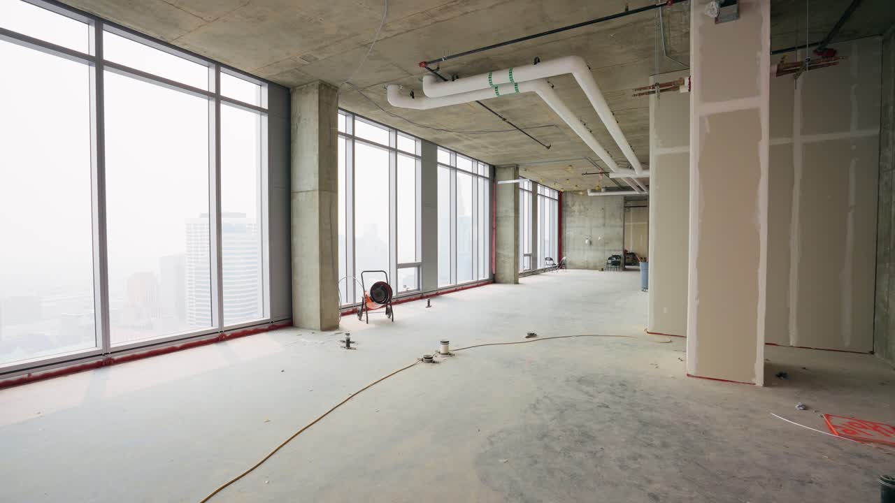Push in shot of an empty penthouse under construction, showcasing the spacious interior and potential design