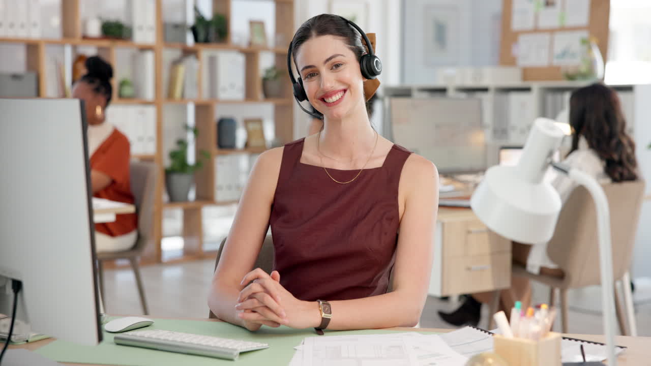 Smilende kvinne med headset som jobber på et moderne kontor.