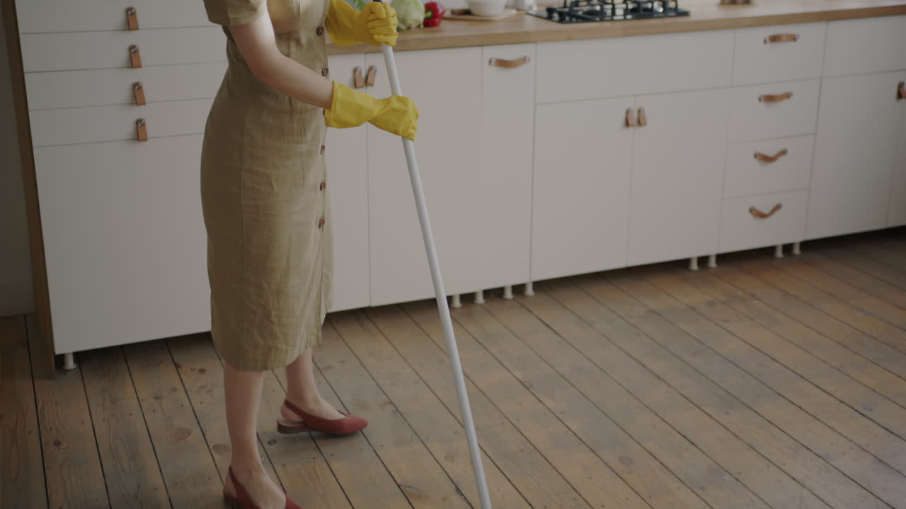 Woman cleaning the wooden floor in a kitchen