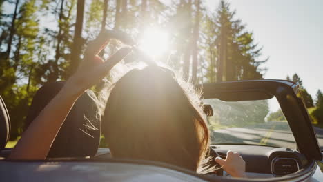 woman driving a convertible through a forest