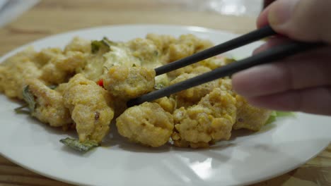 close up shot chopsticks grab singapore salted egg yolk chicken restaurant dish served