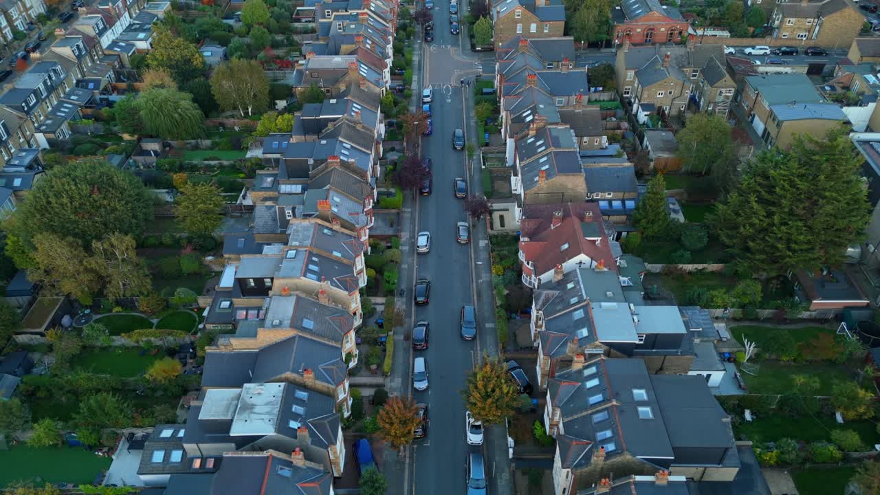 Aerial view quiet residential suburb with rows of tidy houses, gardens and parked cars. Peaceful neighbourhood in summer evening