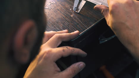 jeweler measures diamonds with ruler on dark table closeup