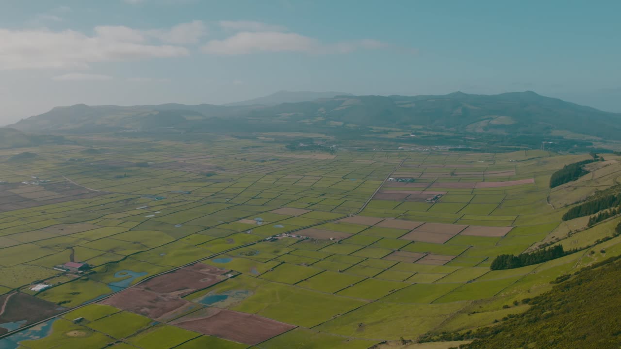Drone video capturing expansive Andalusian farmland with precise geometric crop plots, lush greenery, and distant hills under a clear blue sky, highlighting rural precision