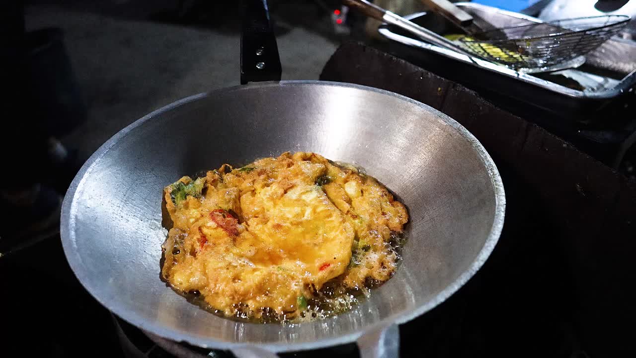 Cucinare una frittata in una padella per strada.