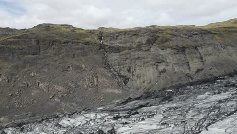 ascend over sólheimajökull glacier with an aerial drone, as the camera reveals the vast icy sprawl and towering mountains beyond, showcasing nature's grandeur and icy realm