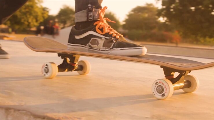 Sunset shot of teenager stepping on skateboard at a skate park.