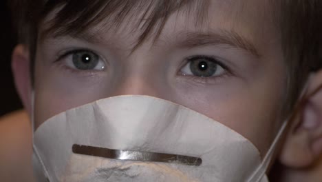 the little boy in a protective mask looks with funky eyes