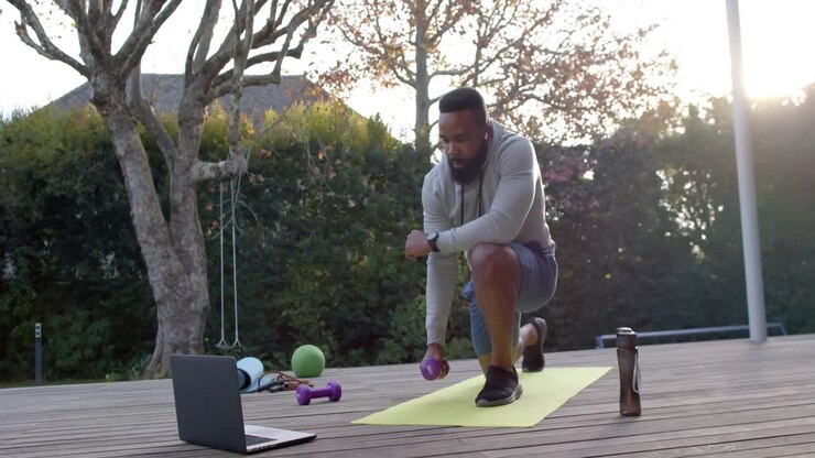 African american man fitness training exercising with weights on deck in sunny garden, slow motion