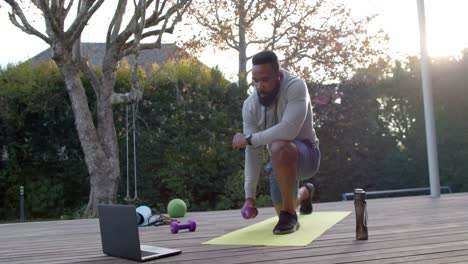 African-american-man-fitness-training-exercising-with-weights-on-deck-in-sunny-garden,-slow-motion