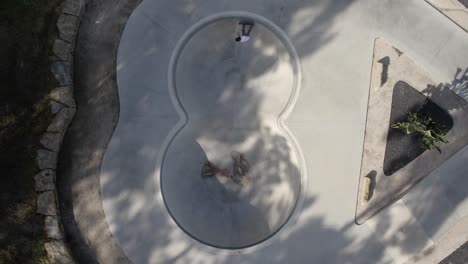 Topdown-view-on-skatepark-pool-and-skateboarder-ride-the-bowl-with-flow