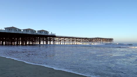 ocean waves hitting the legs of the crystal beach pier, san diego, california