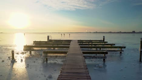 winter landscape in the netherlands with yellow sun and blue sky touching its horizon, durgerdam, amsterdam