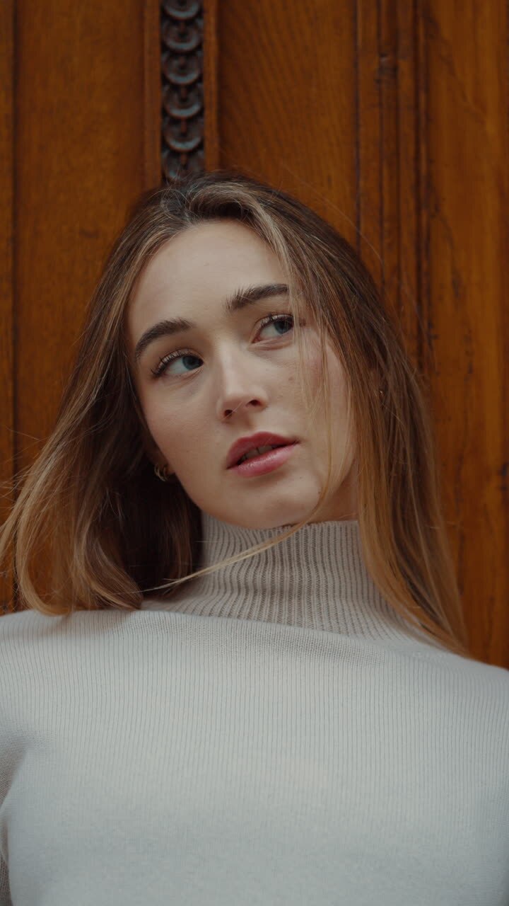 Woman in turtleneck sweater in front of a wooden door