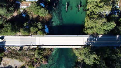 lonely car driving on small bridge over clean river in argentina, aerial top down view