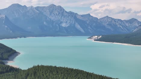 Looking-east-along-Abraham-Lake-in-the-Rocky-Mountains-of-Alberta,-Canada,-as-seen-from-a-drone-as-it-pulls-back-to-reveal-the-turquoise-water