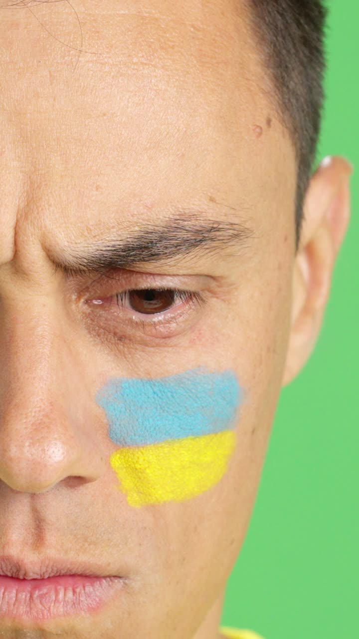Serious man with a ukrainian flag painted on the face