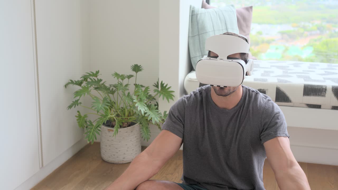Holding VR headset, adult man sitting at home fitting it for VR meditation with smartphone nearby
