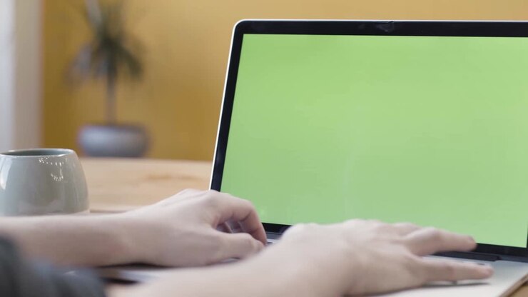 Person, die auf einem Laptop mit grünem Bildschirm tastet