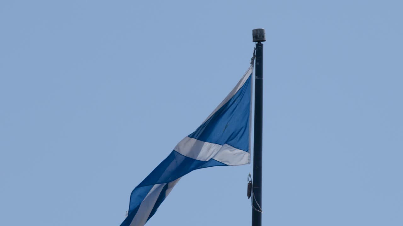 Blue and white flag flutters in daylight breeze, static camera, minimalistic outdoor composition