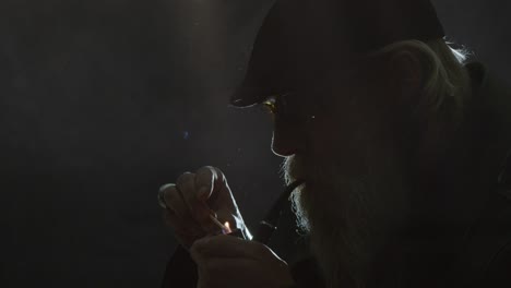 close up hipster man lights pipe in darkness, creative stage lighting