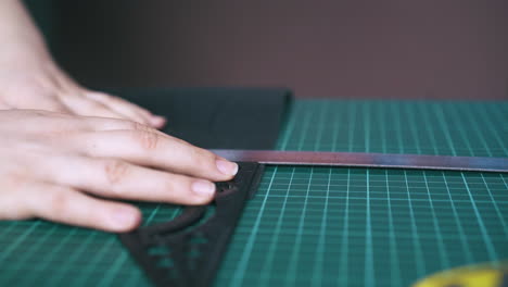 skilled tailor checks measures on black leather fabric