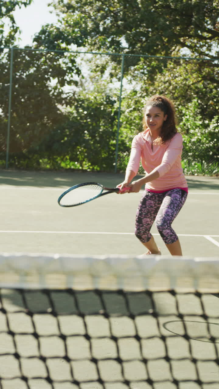 video vertical de una mujer biracial feliz jugando al tenis