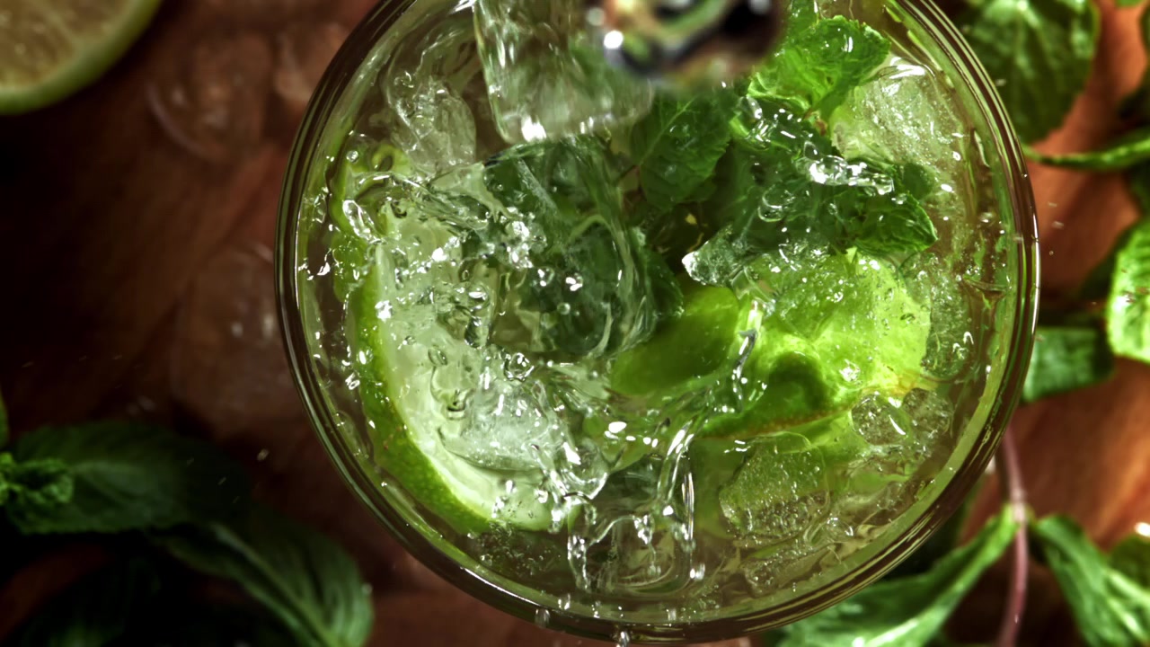 Veden kaataminen virkistävään Mojito-cocktailiin limellä ja mintulla hidastettuna