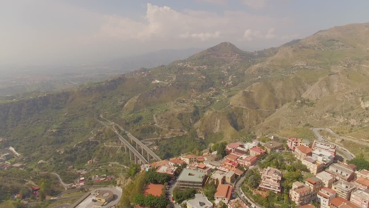 sobrevuelo aéreo de la ciudad elevada de taormina, italia en la cumbre acercándose a los puentes de la autostrada dual a18