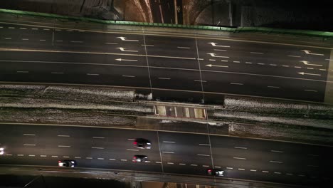 drone shot of night traffic on a motorway showing cars and lanes of light with tunnel and viaducts outside the city of warsaw, poland. moving the camera forward.