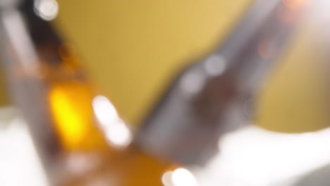 close up de una persona que toma una botella de vidrio refrigerada de cerveza fría o bebidas gaseosas de un cubo lleno de hielo contra un fondo amarillo 2