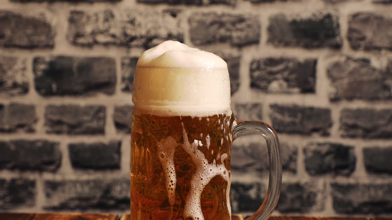 Closeup of filling a glass of beer with foam overflow and slowly floating down