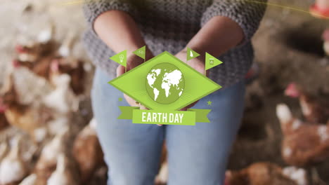 animation of earthday text over caucasian woman holding seeds with chicken in background