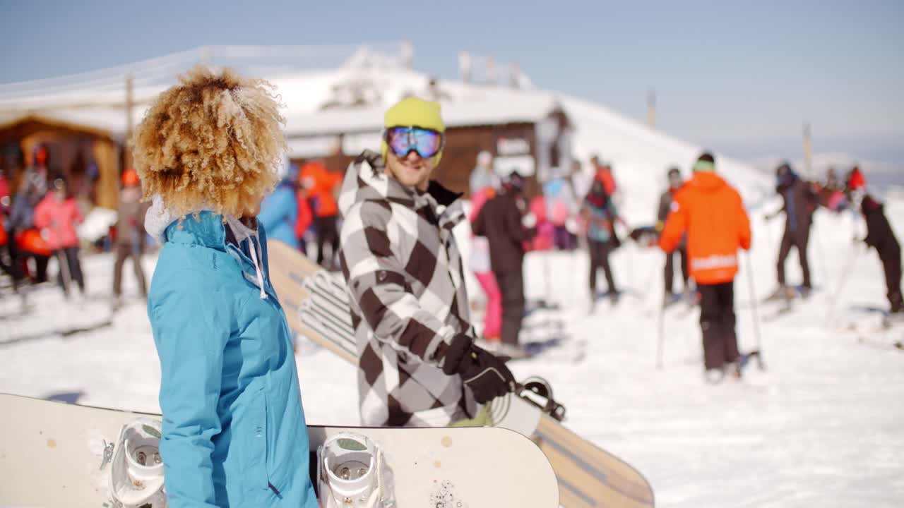 una pareja joven llevando sus snowboards en un complejo