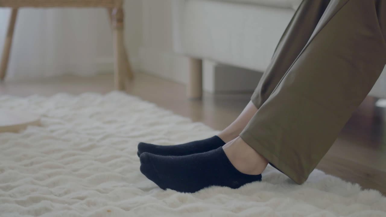Person's feet in black socks on a fluffy white rug