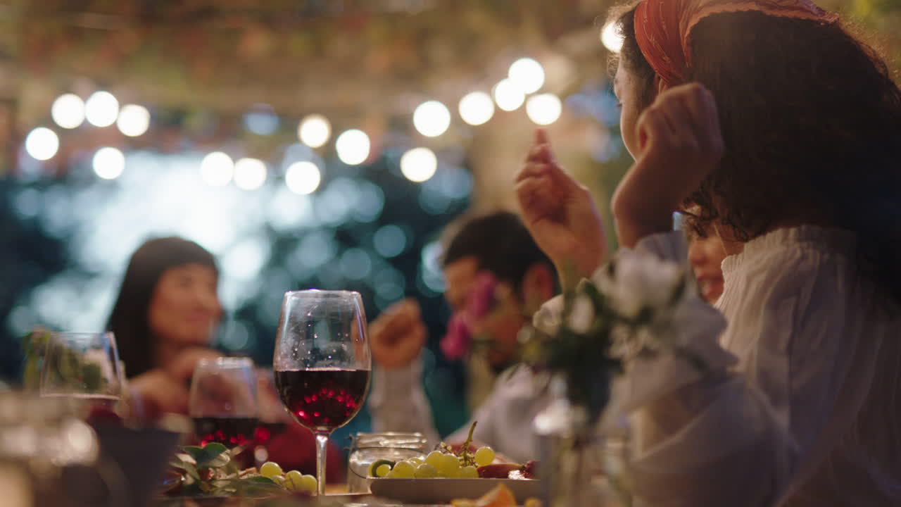 mujer joven bebiendo vino celebrando una cena con amigos charlando juntos disfrutando sentada a la mesa relajándose al aire libre al atardecer