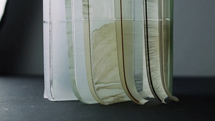 Dripping tan film starting at rightmost panel, coating six transparent panels on studio tabletop