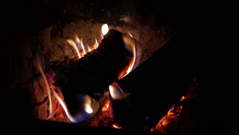 a handheld shot of a crackling fireplace burning in a dark place creating warmth and relaxation